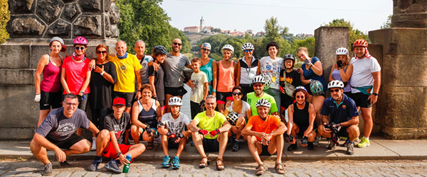 Gruppo di ciclisti in posa davanti a un antico monumento, tour in bici e cultura, la ciclabile dell'Elda e della Moldava