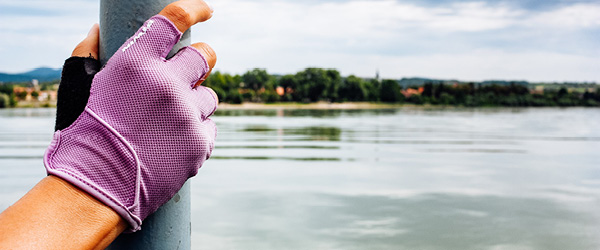 Ciclista con mano appoggiata a un palo sulla sponda del fiume Danubio