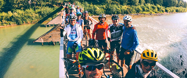 Gruppo di ciclisti in viaggio con Girolibero in posa per una foto su un ponte sospeso in Austria