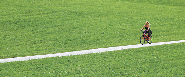 Persona in bicicletta su un sentiero in mezzo a un prato verde in Austria, lungo la ciclabile dei Tauri