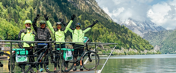 Gruppo di ciclisti su una chiatta che attraversa un lago nel Salzkammergut, con montagne sullo sfondo, viaggi bici e barca 