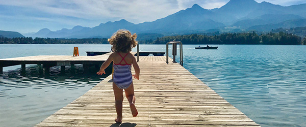 Bambina in costume che corre su una piattaforma in legno per fare un tuffo nel fiume Drava, vacanza in bici, Austria