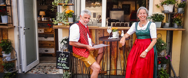 Locale con persone in abiti tradizionali sedute al tavolo fuori, Austria