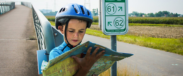 Bambino con caschetto legge una mappa ciclabile, famiglia in bici con Girolibero, Belgio