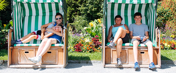 Famiglia di viaggiatori sorridenti che si rilassano su sedie a sdraio lungo il Lago di Costanza, Germania.
