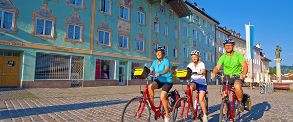 Gruppo di ciclisti in una piazza colorata a Monaco di Baviera, Germania, con edifici storici sullo sfondo, vacanze in bici con 