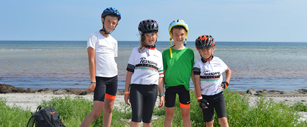 Ragazzi con abbigliamento e caschetto vicino al mare in Danimarca, con biciclette parcheggiate sulla spiaggia, viaggi in bici per famiglie 