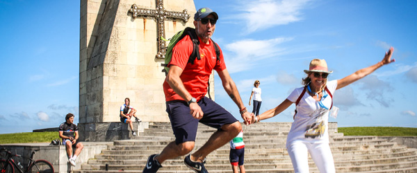 Pellegrini felici davanti a un monumento sull'oceano, viaggiare a piedi, camminare in Spagna, cammino sulla costa da Finisterre a Muxia, Galizia