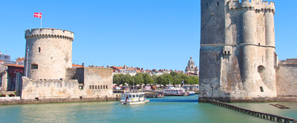 Torre e porto antico a La Rochelle con cielo azzurro e mare calmo, Francia