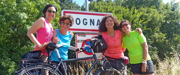 Cicliste sorridenti fanno una foto davanti a un cartello con la scritta 
