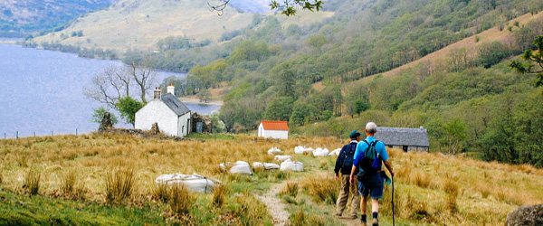 Escursionista su un sentiero lungo un lago nelle Highlands scozzesi, trekking organizzati 