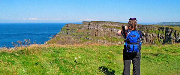 Escursionista su un sentiero verde che costeggia una scogliera nell'Irlanda del Nord.