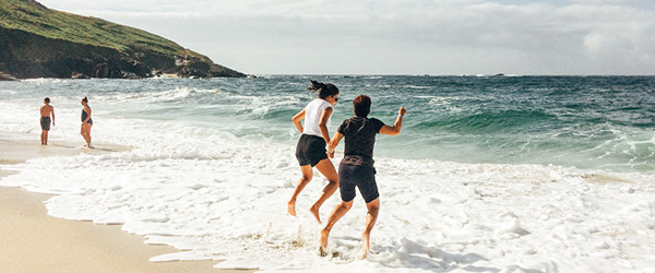 Famiglia che gioca tra le onde su una spiaggia sabbiosa in Cornovaglia.
