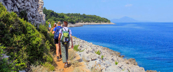 Gruppo escursionisti in cammino lungo la costa di Lussino, Croazia, trekking con 