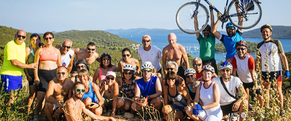 Gruppo di ciclisti sorridenti su una collina panoramica sul mare, Croazia , viaggi in bici a barca 