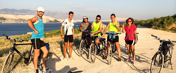 Group of cyclists resting on a beach on the Dalmatian coast, bike and boat trips 