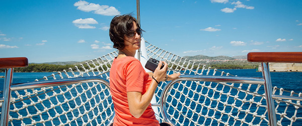 Donna con macchina fotografica sul ponte di una barca, vacanze in bici e barca con 