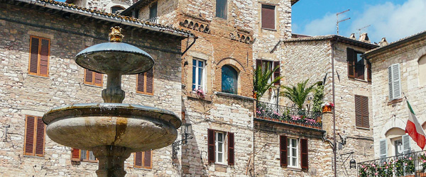 Piazza del Comune, Assisi, con balconi fioriti e architettura medievale.