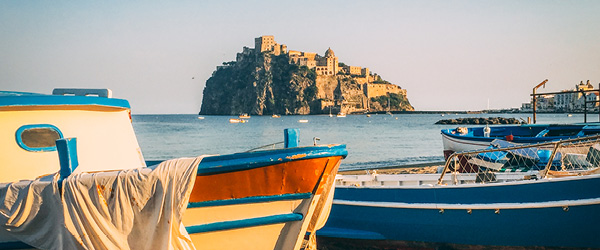 Barche colorate in primo piano ormeggiate su una spiaggia a Ischia, Italia.
