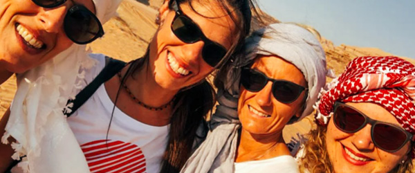 Gruppo di amiche sorridenti con occhiali da sole nel deserto di Wadi Rum, Giordania.
