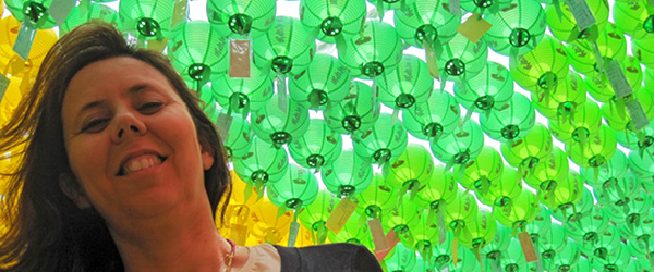 Donna sorridente in viaggio con Girolibero sotto lanterne verdi durante una festa in Corea del Sud.