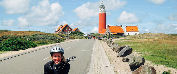 Ciclista in viaggio con Girolibero davanti al faro dell'isola di Texel, Olanda.