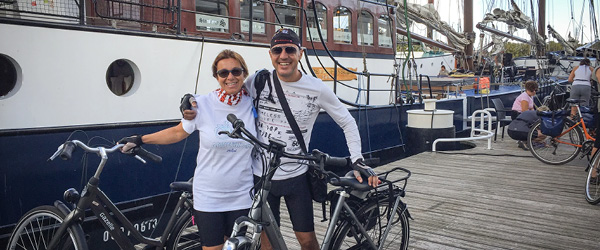 Paar Radfahrer vor einem Boot, das im Hafen der friesischen Inseln festgemacht hat, 