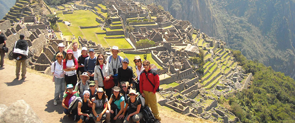 Gruppo di turisti a Machu Picchu con vista sulle antiche rovine Inca e montagne peruviane, tour 