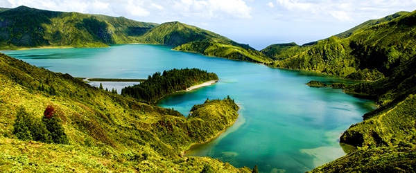 Escursionisti vicino a un lago panoramico circondato dal verde nell'Isola di San Miguel, Azzorre.