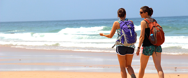 Due persone che camminano sulla spiaggia lungo l'Oceano, trekking sulla Rota vicentina