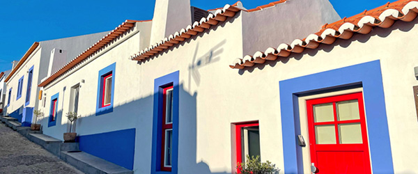 Case bianche con porte e finestre colorate in un villaggio portoghese lungo la Rota Vicentina.
