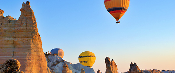 Mongolfiere sorvolano le formazioni rocciose della Cappadocia, Turchia, all’alba