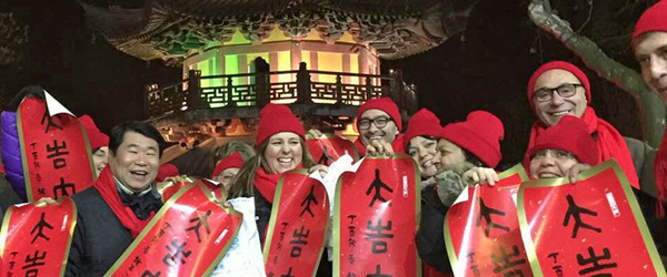 Gruppo di viaggiatori davanti a una pagoda illuminata nel centro storico di Shanghai durante un tour serale in Cina