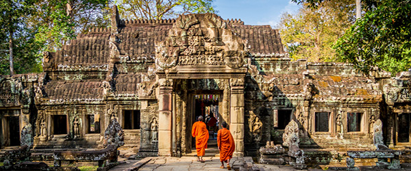 Monaci buddisti in abito arancione che varcano il tempio Preah Khan nel Parco Archeologico di Angkor, Cambogia
