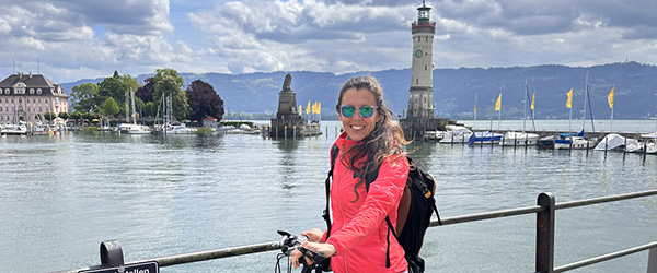 Ciclista sul lungolago di Costanza con vista sul porto di Lindau e sul faro del Bodensee.