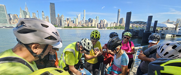 Gruppo di cicloturisti Girolibero durante un tour in bicicletta a New York con vista sullo skyline di Manhattan.