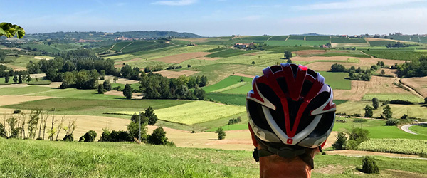Turista in bicicletta si rilassa in un campo dorato nelle campagne del Monferrato.