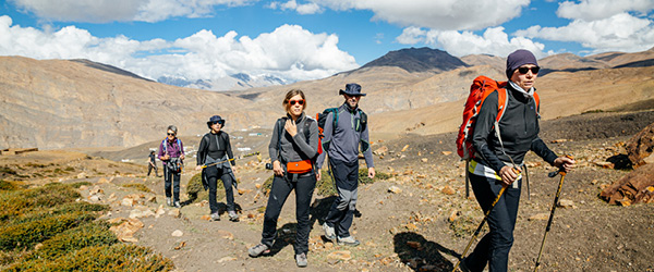 Gruppo di viaggiatori in trekking su altopiano montano in area himalayana, viaggio a piedi tra paesaggi d’alta quota