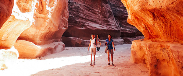 Escursionisti nel Siq di Petra, canyon di roccia rossa in Giordania, viaggio trekking tra le meraviglie nabatee