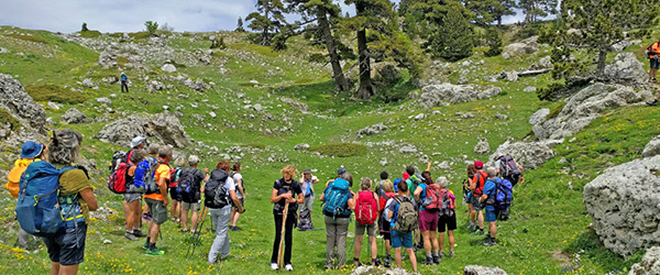 Gruppo di escursionisti in cammino su altopiano roccioso della Basilicata, trekking guidato tra pascoli e paesaggi selvaggi dell’Appennino lucano
