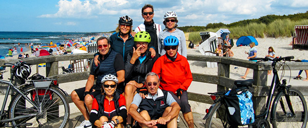 Gruppo di ciclisti si ferma per una pausa su una passerella con vista sul mare Baltico, vacanze di gruppo in bici 