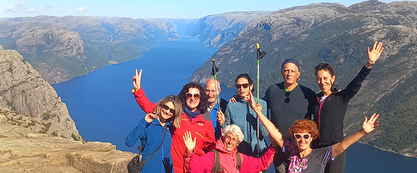 Gruppo di viaggiatori in cima a un punto panoramico in Norvegia, escursione di gruppo tra montagne e fiordi norvegesi durante un viaggio attivo Girolibero.