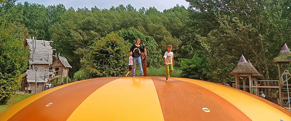 Bambini che giocano su una grande struttura ludica arancione in un parco urbano dei Paesi Bassi, esperienza all’aria aperta durante una vacanza in famiglia.