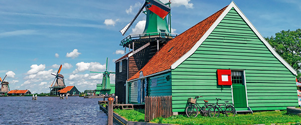 Mulino a vento tradizionale olandese accanto a casa verde sul canale a Zaanse Schans.