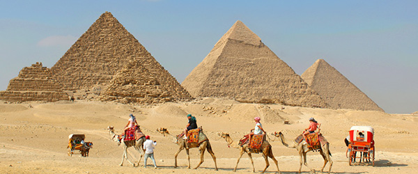 Piramidi di Giza con carovana di cammelli nel deserto, una delle attrazioni più iconiche dell'Egitto.