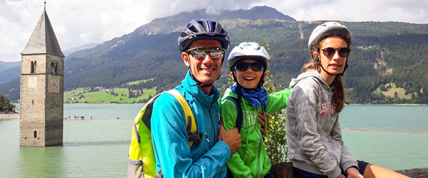 Famiglia davanti al Lago di Resia e al campanile sommerso, Alto Adige.
