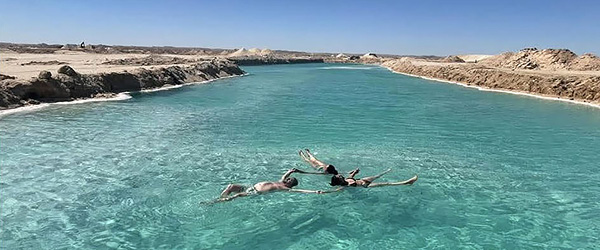 Laguna turchese nel deserto egiziano con persone che nuotano