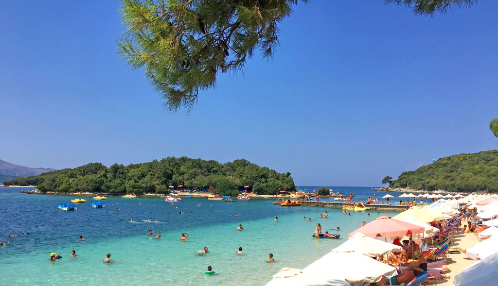 Baia con acque cristalline e barche ancorate vicino alla costa albanese.