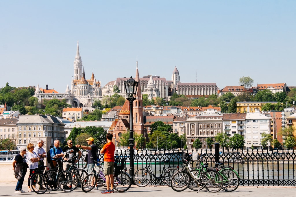 Ciclisti con vista sulla città e sul fiume, con cattedrale in lontananza.