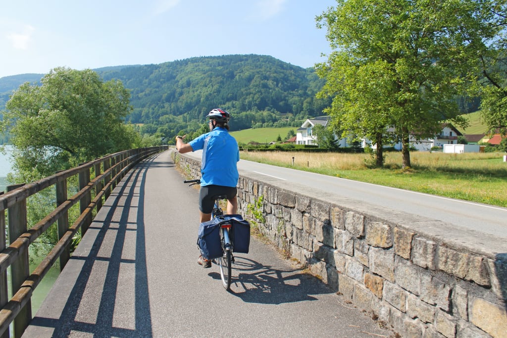 Ciclista su un percorso immerso nelle verdi colline lungo la Ciclabile del Danubio, Austria